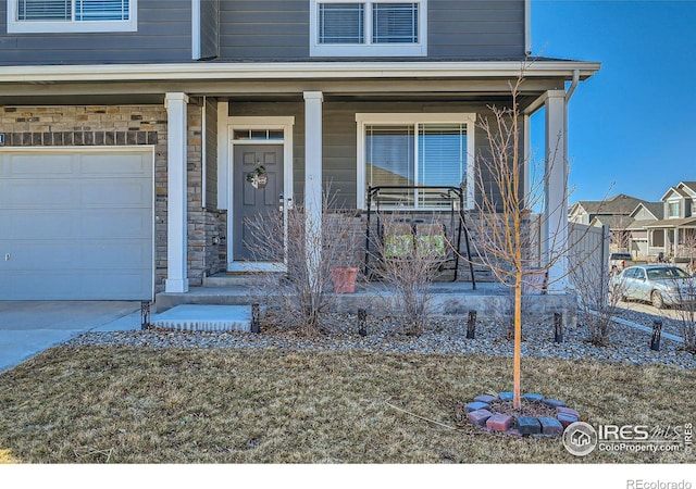 property entrance with a garage, covered porch, and stone siding