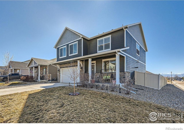 view of front of home with covered porch, an attached garage, fence, stone siding, and driveway