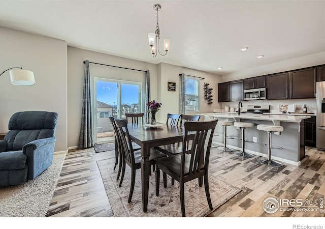 dining area featuring light wood-type flooring, recessed lighting, baseboards, and an inviting chandelier