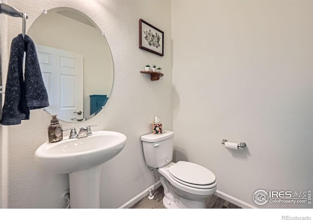 bathroom with toilet, baseboards, and a sink