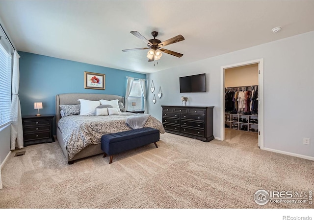 bedroom with baseboards, ceiling fan, carpet, a walk in closet, and a closet