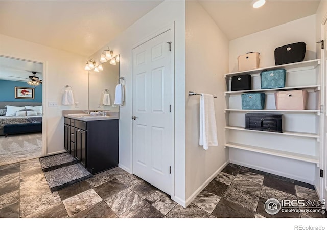 bathroom with a ceiling fan, stone finish flooring, connected bathroom, vanity, and baseboards