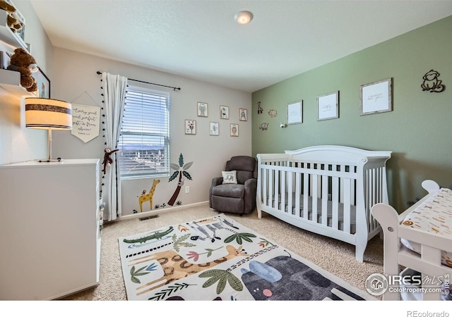 bedroom with a nursery area, carpet floors, visible vents, and baseboards