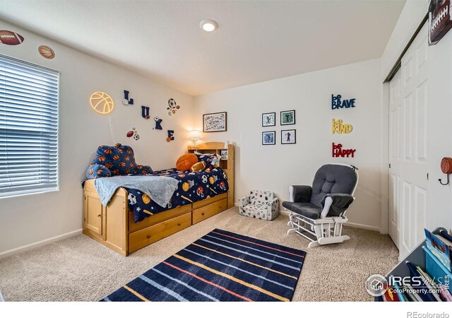 carpeted bedroom featuring baseboards and a closet