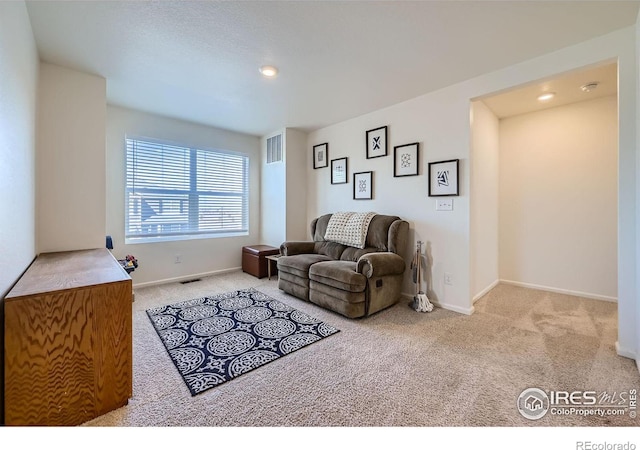 living area with carpet floors, baseboards, and visible vents