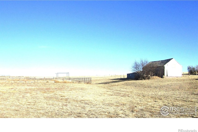 view of yard featuring an outbuilding, a rural view, and fence