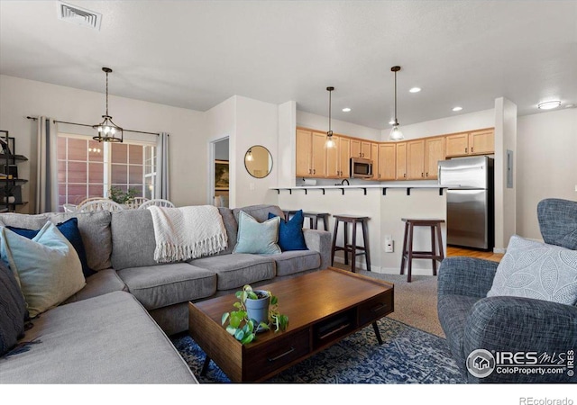 living room with an inviting chandelier, visible vents, light colored carpet, and recessed lighting