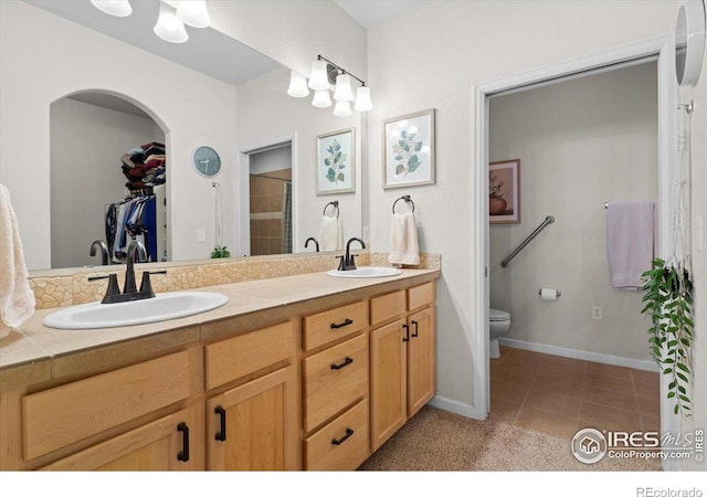 full bathroom with tile patterned floors, a sink, toilet, and double vanity