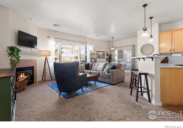 living room featuring a textured ceiling, carpet, a fireplace, and visible vents