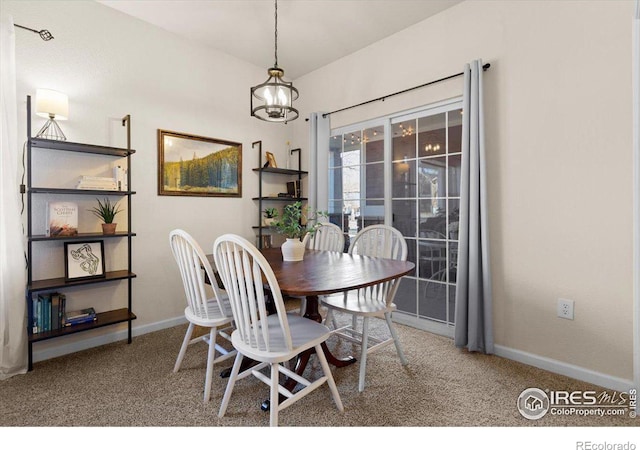 dining space with carpet, baseboards, and a notable chandelier