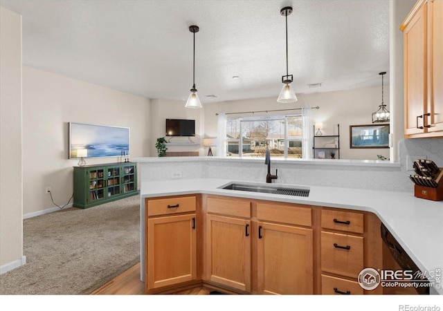 kitchen featuring open floor plan, hanging light fixtures, a peninsula, light countertops, and a sink