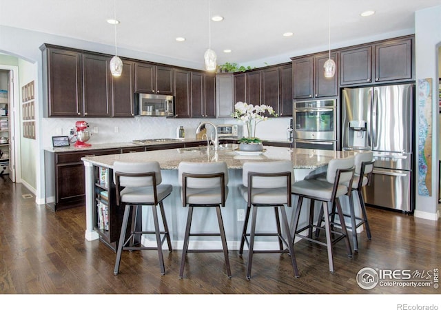 kitchen with dark brown cabinetry, dark wood-style floors, and appliances with stainless steel finishes