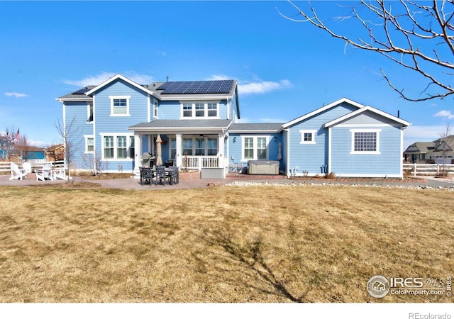 back of property featuring a patio area, solar panels, and a yard