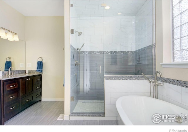 full bath with a stall shower, a freestanding bath, and vanity