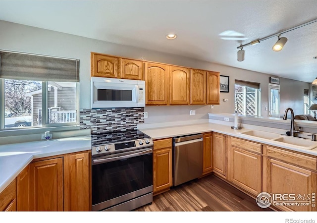 kitchen featuring dark wood finished floors, tasteful backsplash, light countertops, appliances with stainless steel finishes, and a sink