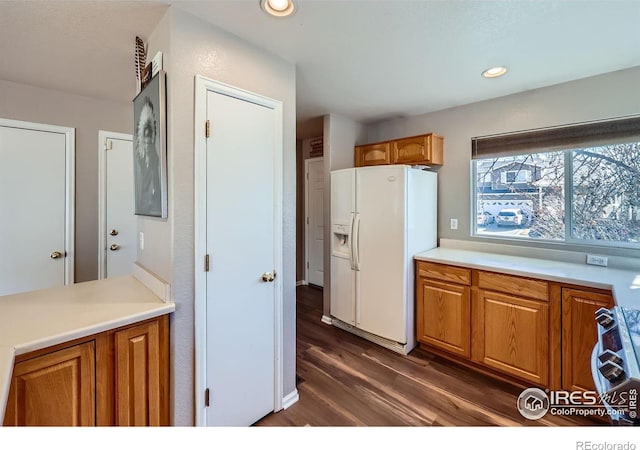 kitchen featuring brown cabinets, white refrigerator with ice dispenser, and range