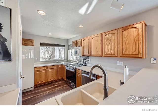 kitchen featuring dark wood finished floors, stainless steel appliances, a textured ceiling, light countertops, and a sink