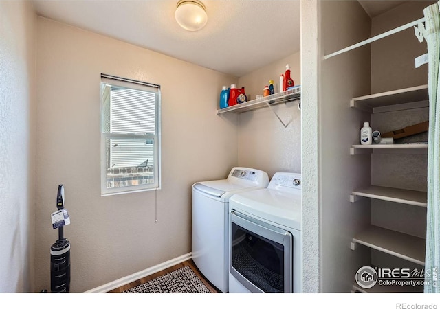 laundry area featuring laundry area, wood finished floors, washing machine and dryer, and baseboards