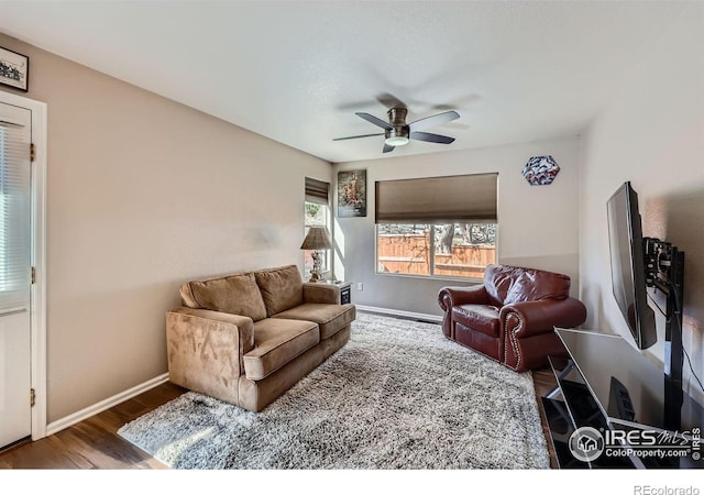 living area with a ceiling fan, baseboards, and wood finished floors