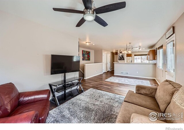 living room with wood finished floors, a ceiling fan, visible vents, baseboards, and rail lighting