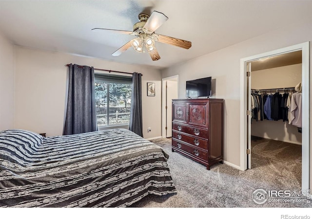 carpeted bedroom with a closet, ceiling fan, a spacious closet, and baseboards