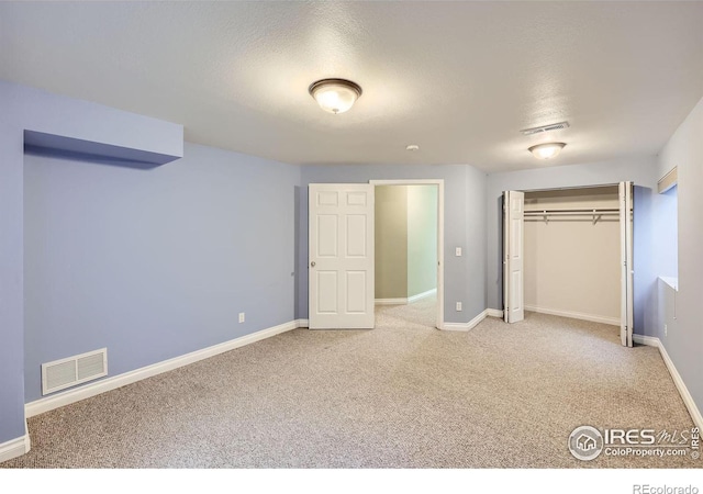 unfurnished bedroom with a closet, carpet flooring, visible vents, and baseboards