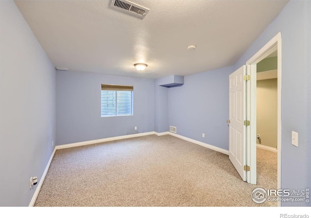 carpeted empty room with a textured ceiling, visible vents, and baseboards