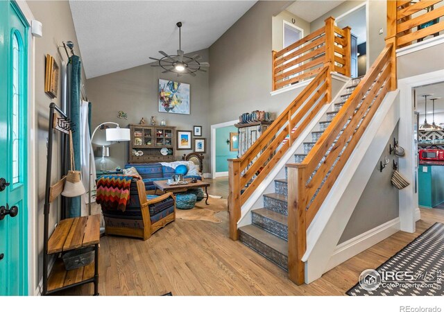 interior space with high vaulted ceiling, baseboards, a ceiling fan, and wood finished floors