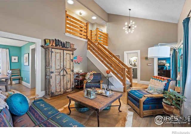 living area with stairway, a high ceiling, an inviting chandelier, wood finished floors, and baseboards