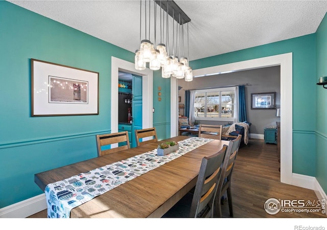 dining space featuring a textured ceiling, baseboards, wood finished floors, and a notable chandelier