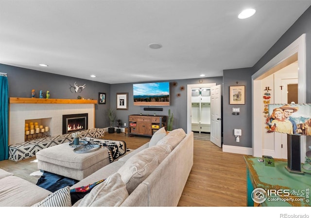 living room featuring a fireplace, baseboards, wood finished floors, and recessed lighting