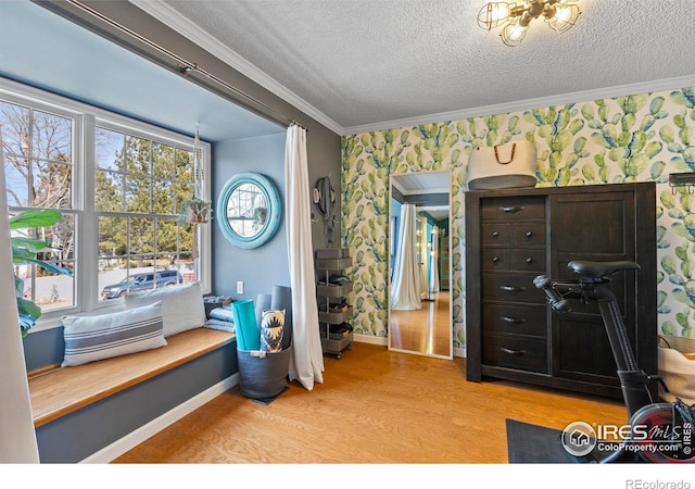 interior space with a textured ceiling, wallpapered walls, light wood-style floors, and crown molding