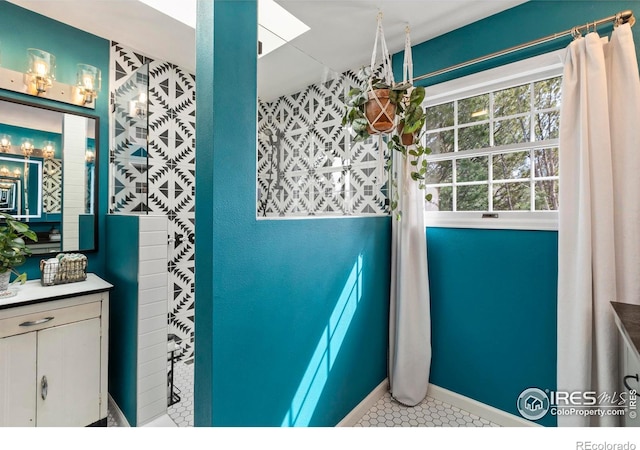 bathroom with a skylight, vanity, and tile patterned floors