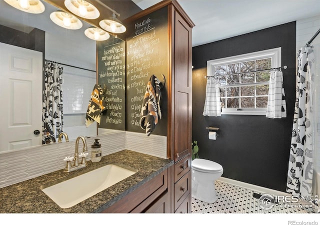 bathroom featuring toilet, baseboards, and vanity