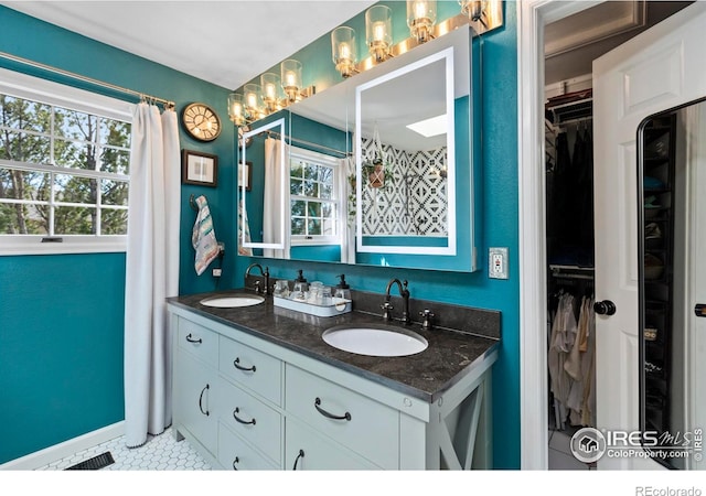 full bath featuring a walk in closet, a sink, and tile patterned floors