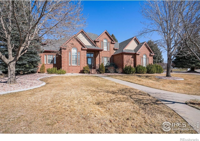 traditional home with a shingled roof, brick siding, and a front lawn