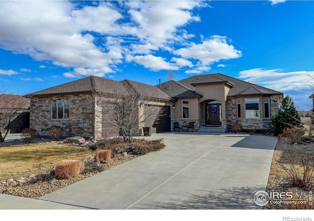 prairie-style house featuring a garage, concrete driveway, stone siding, and stucco siding