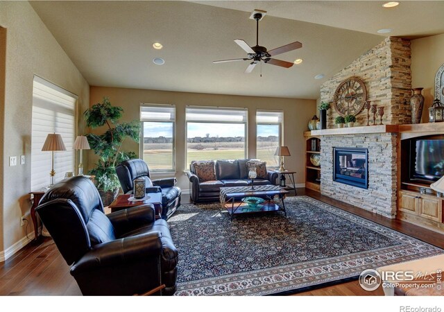 living room featuring baseboards, wood finished floors, vaulted ceiling, a fireplace, and recessed lighting