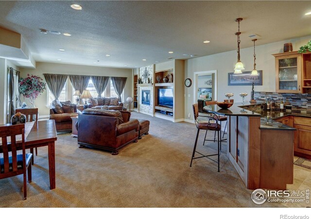 living area featuring light carpet, baseboards, a textured ceiling, a fireplace, and recessed lighting