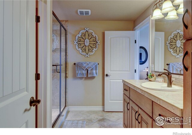 bathroom featuring visible vents, a stall shower, vanity, and baseboards