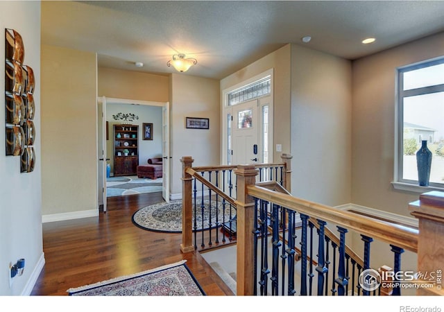 hallway with recessed lighting, wood finished floors, an upstairs landing, and baseboards