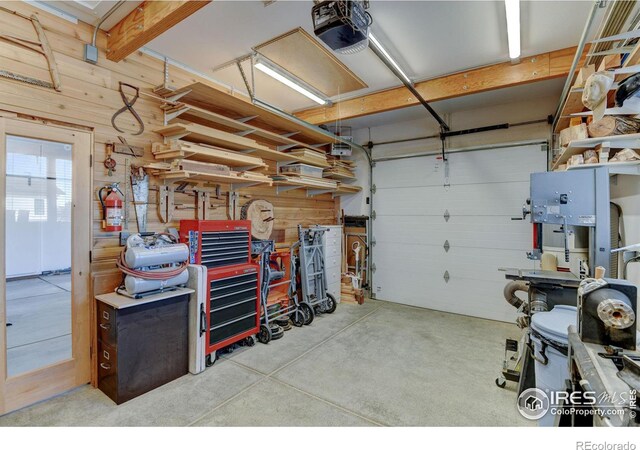 garage with wood walls, a workshop area, and a garage door opener