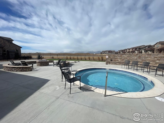 view of swimming pool featuring a hot tub, a patio area, a fenced backyard, and a fire pit