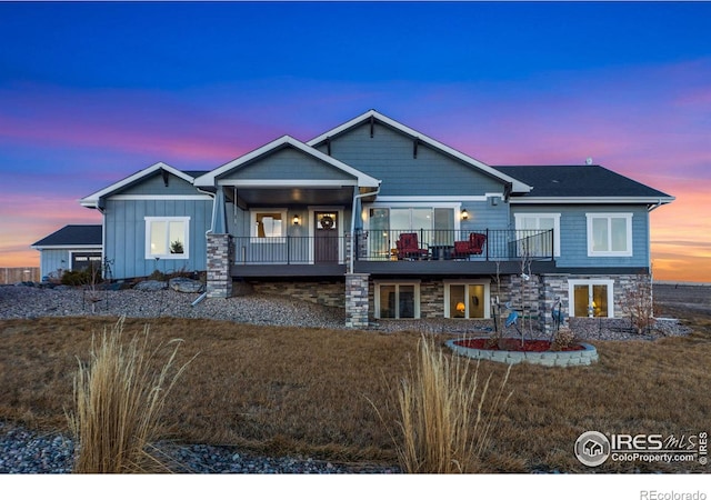 view of front of property featuring a deck, stone siding, and board and batten siding