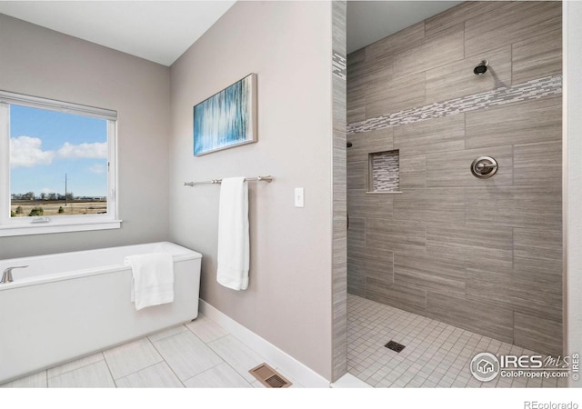 bathroom featuring tiled shower, a bathtub, visible vents, and baseboards