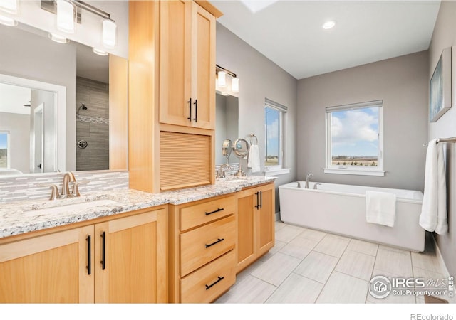 full bath with a tile shower, double vanity, a freestanding tub, and a sink