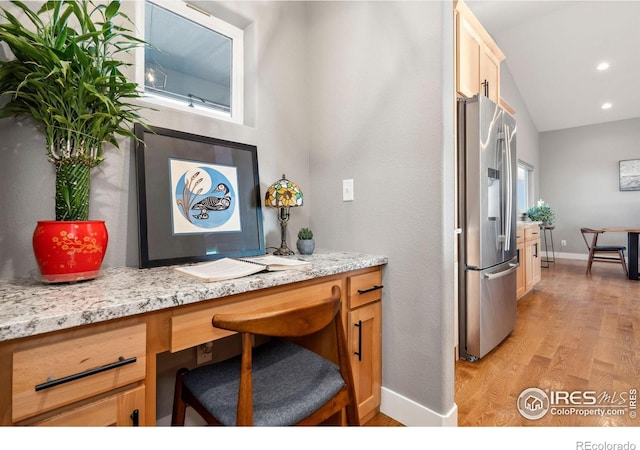 kitchen with stainless steel fridge, baseboards, built in study area, light wood-style flooring, and vaulted ceiling