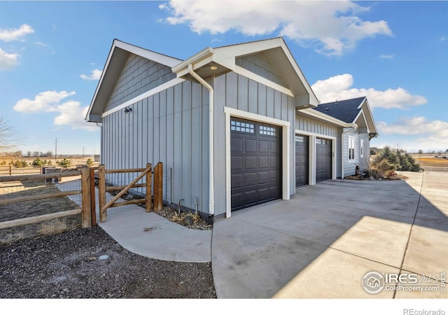 garage with a gate, driveway, and fence