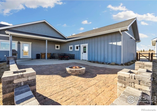 back of house featuring a fire pit, board and batten siding, a patio area, and fence