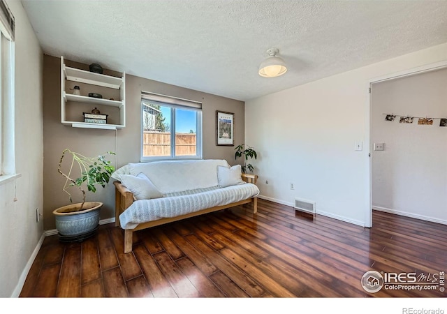 sitting room with visible vents, a textured ceiling, baseboards, and wood finished floors